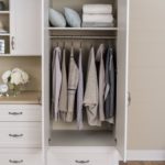 Open cabinet door with clothing on rack