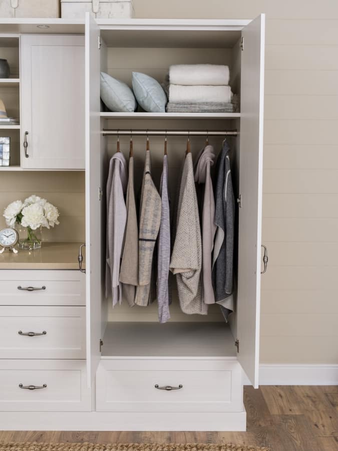 Open cabinet door with clothing on rack