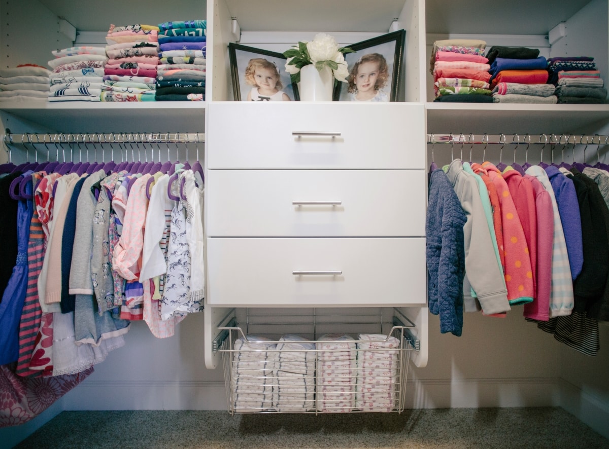 Children's closet full of shoes on shelves and clothing on shelves and hung up on racks