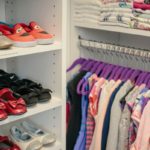 Closet up of children's shoes on shelves and clothes hung on racks and folded on shelves