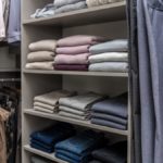 Clothing folded on shelves in closet