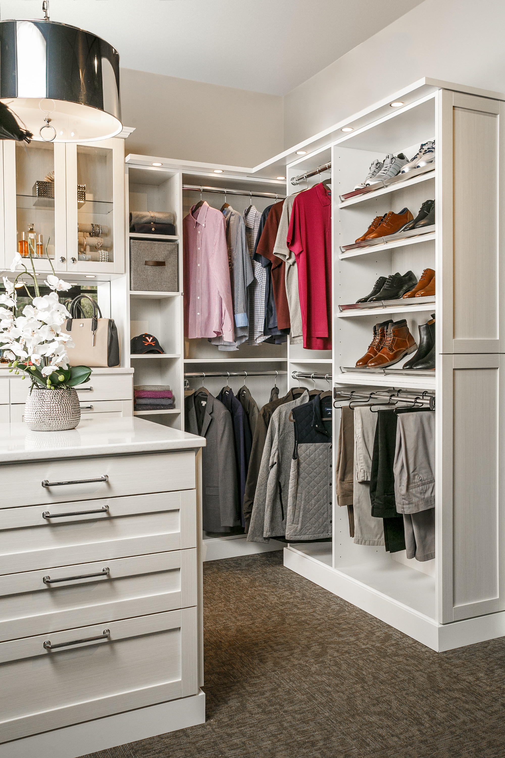 Corner view of closet with shoes on shelves, clothing on racks and other articles in cabinets