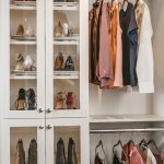 Closet with shoes in cabinets and shirts hung on racks