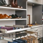 Side view of shoes and socks on shelves as well as pants hung on clothing racks