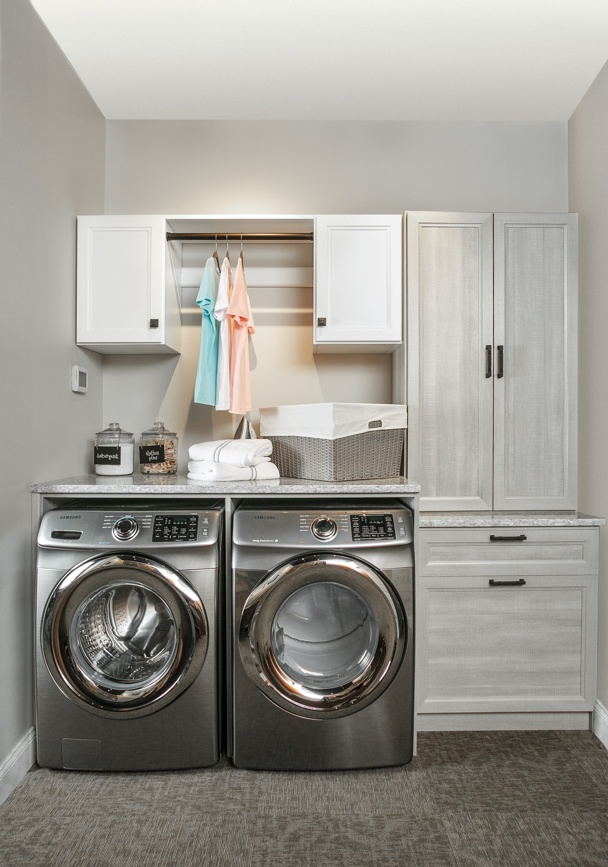 Laundry closet showing rack for hanging clothing as well as space for washer and dryer