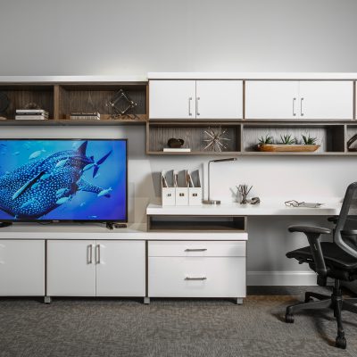 Entertainment center showing television, articles on shelves and office chair at desk