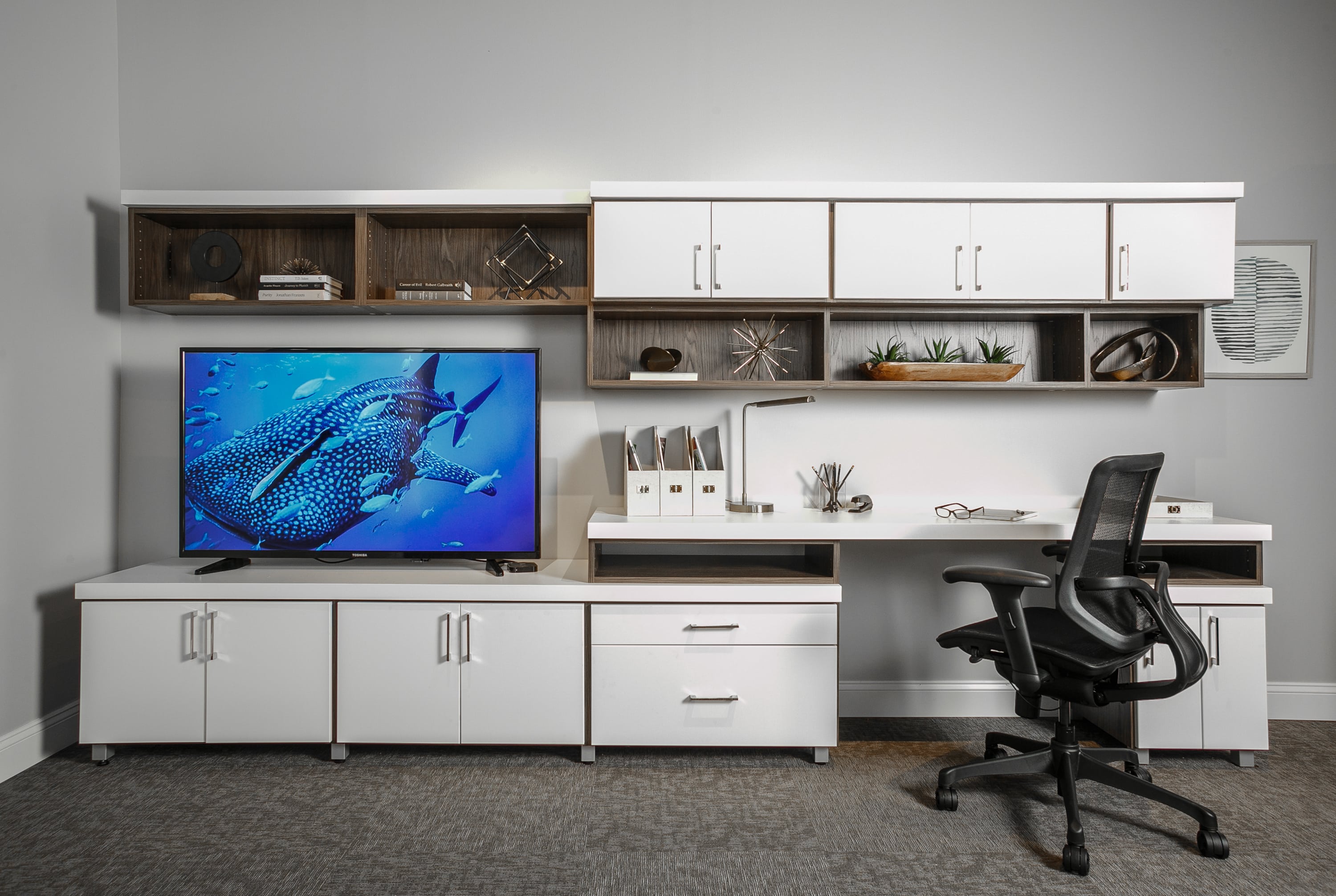 Entertainment center showing television, articles on shelves and office chair at desk