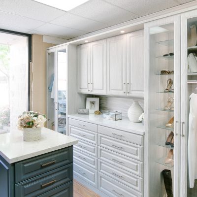 Beautiful floor mounted closet with glass door wardrobe and island drawers in Sacramento