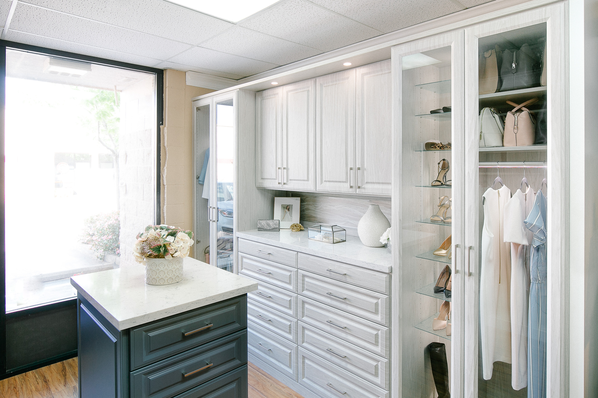 Beautiful floor mounted closet with glass door wardrobe and island drawers in Sacramento