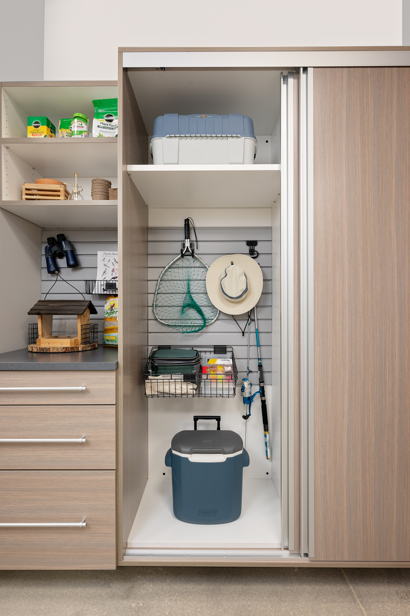 Custom wall mounted garage storage in driftwood with sliding cabinet doors in Port St. Lucie, Florida