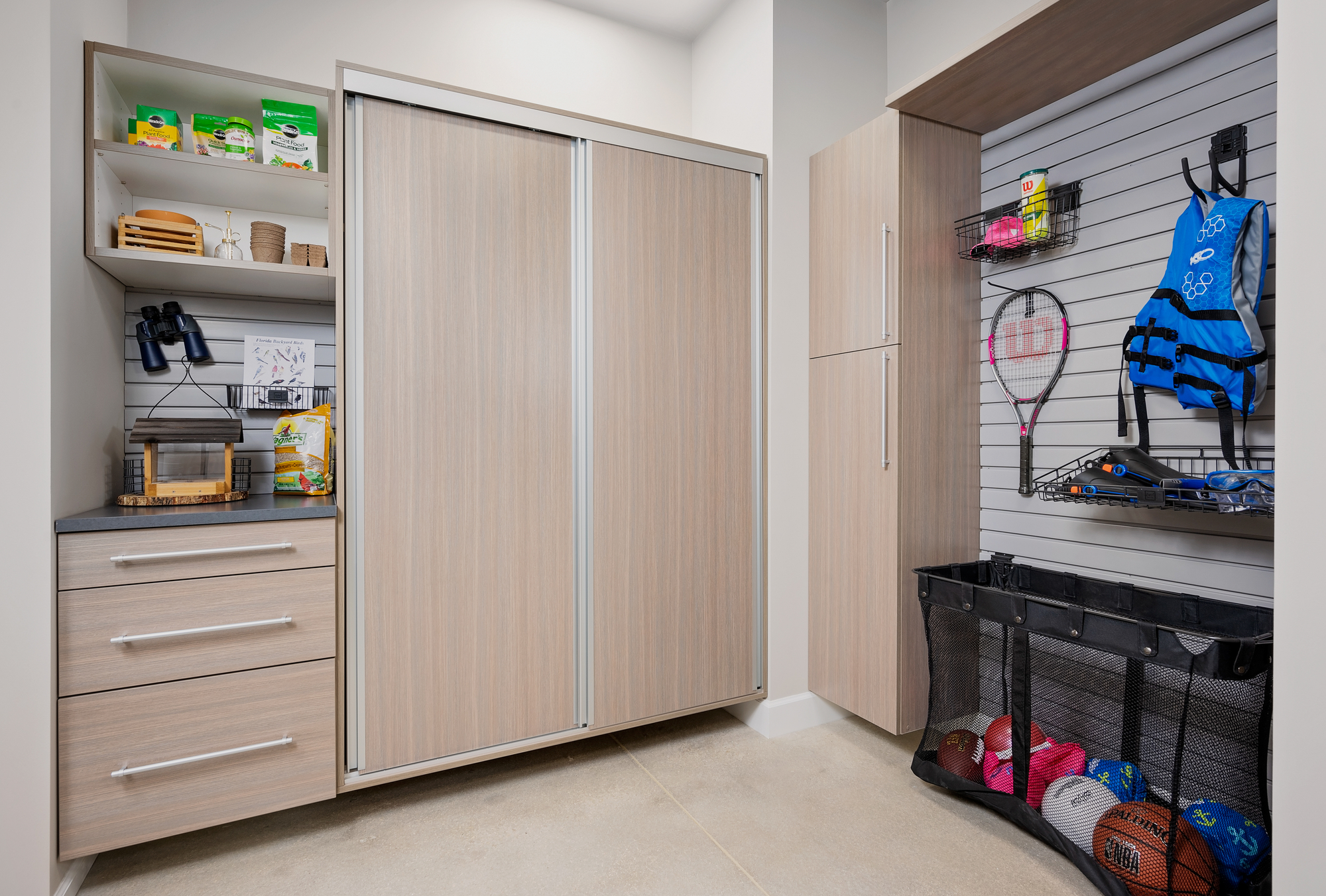 Custom wall mounted garage storage in driftwood with sliding cabinet doors in Vero Beach, Florida